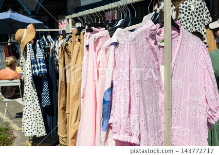 Stylish summer clothing collection on outdoor market rack with pastel linen fashion and casual apparel Stylish summer clothing collection on outdoor market rack with pastel linen fashion and casual apparel 143772717