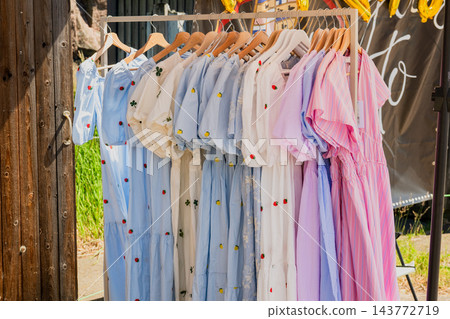 Stylish summer clothing collection on outdoor market rack with pastel linen fashion and casual apparel Stylish summer clothing collection on outdoor market rack with pastel linen fashion and casual apparel 143772719