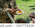Ukrainian soldiers serving food from thermal containers outdoors 143773416