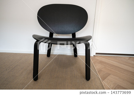Modern black wooden chair in minimalist interior on carpet near white wall 143773699