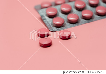 Pink tablets pill on blur blister pack of tablets pills on pink background. Prescription drugs. Woman health concept. Pharmaceutical industry. Online pharmacy banner. Drugs packaging. Treatment dose. Pink tablets pill on blur blister pack of tablets pills on pink background. Prescription drugs. Woman health concept. Pharmaceutical industry. Online pharmacy banner. Drugs packaging. Treatment dose. 143774576