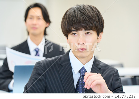 一位年輕的辦公室職員正在辦公室與團隊成員一起查看文件。 143775232