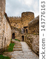 Stone steps and cobbled path through Ananuri fortress courtyard with round tower and arched doors 143776163