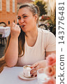 Woman Enjoying Coffee and Dessert at Outdoor Cafe 143776481