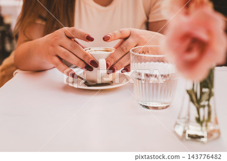 Woman Holding Coffee Cup at Outdoor Cafe 143776482