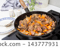 Roast veal liver is being cooked in a skillet with diced carrots and onions. The cooking takes place on a stove in a kitchen. The meal looks ready to be served 143777931