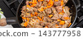 Cook prepares roast veal liver by cutting it into pieces. Nearby, there are chopped onions and carrots on a wooden board. The skillet is on the stove ready for cooking, banner 143777958