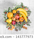 Festive arrangement of colorful fruit in a white wooden crate with evergreen branches, pinecones and cinnamon 143777973