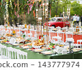 Elegant outdoor wedding banquet with long dining tables, white chairs and abundant floral arrangements. 143777974