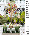 Beautiful outdoor wedding reception with decorated dining tables, white chairs, hanging flowers 143777975