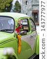 Vintage green automobile decorated with flowers and a colorful ribbon for a wedding celebration. 143777977