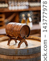 Traditional wooden wine barrel with a tap displayed on a rustic wooden surface inside a winery. 143777978