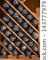 Rows of wine bottles stored in a traditional wooden rack inside a winery cellar. 143777979