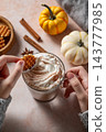 Hands in a knitted sweater hold a waffle cookies and a cup of pumpkin latte 143777985