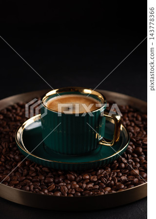 Fresh espresso in green and gold cup surrounded by roasted beans Fresh espresso in green and gold cup surrounded by roasted beans 143778366