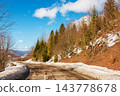 old country road in Carpathian mountains of Ukraine. landscape in late winter. trees on the roadside in morning light. blue sky with fluffy clouds above the distant ridge. travel background 143778678