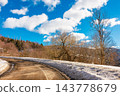 old country road in Carpathian mountains of Ukraine. landscape in late winter. trees on the roadside in morning light. blue sky with fluffy clouds above the distant ridge. travel background 143778679