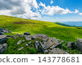 Carpathian mountain summer landscape. meadow with huge stones among the grass on top of the hillside near the peak of mountain range dappled light. clouds on the sky 143778681