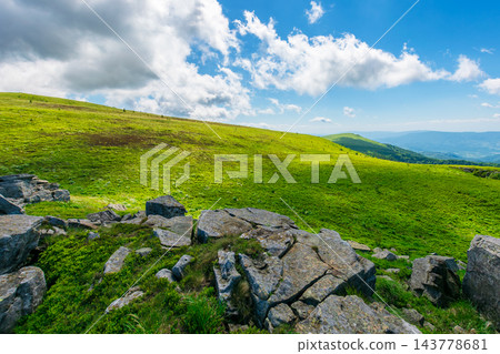 Carpathian mountain summer landscape. meadow with huge stones among the grass on top of the hillside near the peak of mountain range dappled light. clouds on the sky 143778681