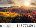 sunset over hillside of mountain range with mixed forest and alpine meadow in autumn colors. Apuseni national park under cloudy sky with rainbow. Romania in fall season 143778691