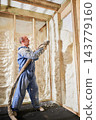 Contractor insulating timber wall sections with polyurethane foam spray. House interior under construction, thermal barrier, retrofit work and comfort concept 143779160