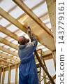 Worker spraying polyurethane foam insulation under roof in timber frame house. Energy efficient construction, home renovation, weatherization, sustainable housing, modern building technology concept 143779161