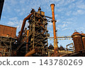 Vertical photo of historic blast furnace steel framework with bright orange conical exhaust stack multi tier catwalk stairs and rusty gas pipelines in Duisburg Ruhr region Westphalia Germany 143780269