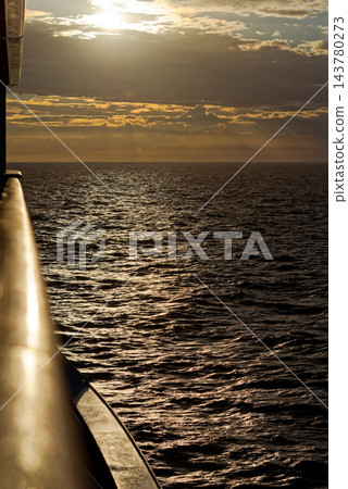 Golden sunset over shimmering sea from ship rail Golden sunset over shimmering sea from ship rail 143780273