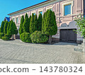 Facade of two-story house is decorated with green thuja trees 143780324