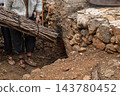 Man in Traditional Rustic Attire Carrying Firewood Bundle to an 143780452