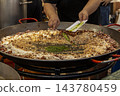 Chef adding green herb paste to large traditional Spanish seafoo 143780459