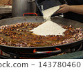Chef Adding White Rice to a Traditional Spanish Seafood Paella i 143780460
