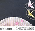 A fan with a folded crane and floral pattern against a black background. 143781805