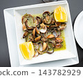 Delicious lemon herb clams served in white bowl 143782929
