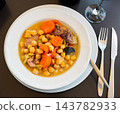 Popular dish of Spanish cuisine is Cocido de garbanzos, made from meat, vegetables and chickpeas, closeup 143782933