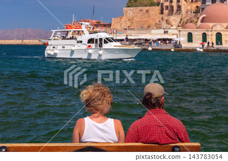 Two People on a Bench Overlooking Chania Venetian Harbor, Crete, Greece Two People on a Bench Overlooking Chania Venetian Harbor, Crete, Greece 143783054