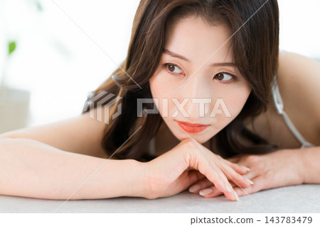 一位美麗的女子雙臂搭在桌上,陷入沉思。 (美容/化妝品) 一位美麗的女子雙臂搭在桌上,陷入沉思。 (美容/化妝品) 143783479