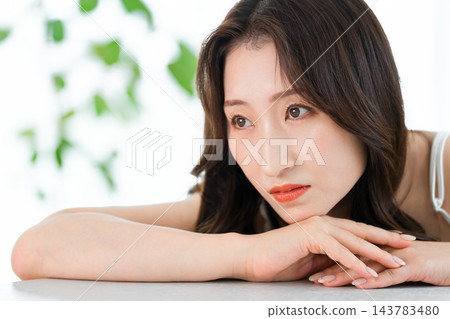 一位美麗的女子雙臂搭在桌上,陷入沉思。 (美容/化妝品) 一位美麗的女子雙臂搭在桌上,陷入沉思。 (美容/化妝品) 143783480