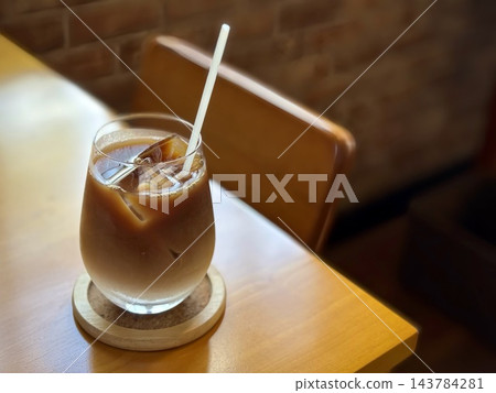 畫面中有一張木桌和一杯冰拿鐵。 143784281