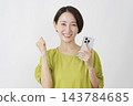 一位中年婦女在白色背景前舉著智慧型手機，做出勝利的手勢。 143784685