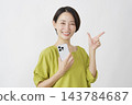 一位中年婦女手持智慧型手機，在白色背景前比劃了一個勾號。 143784687
