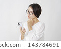 一位中年婦女在白色背景下使用智慧型手機思考。 143784691