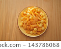 Bowl of cheese crackers and puffed snacks on a wooden table 143786068
