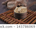 Ground cinnamon powder in a wooden cup with cinnamon sticks 143786069