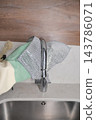 Hands remove a mesh sink strainer from a kitchen faucet 143786071