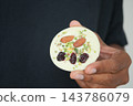 Hand holding a round white dessert topped with almonds and pistachios 143786079