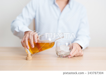 man pour whiskey into a glass on table, suffering from alcohol addiction, alcoholism concept. depicting emotional distress, depression, substance abuse problem, unhealthy lifestyle and mental health 143787304