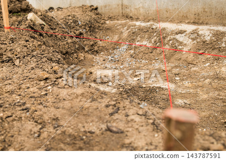 Bright red measurement lines stand out on the freshly excavated soil, outlining the foundation layout. Bright red measurement lines stand out on the freshly excavated soil, outlining the foundation layout. 143787591