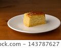 Delicious golden cake slice on a white plate inviting sweet indulgence 143787627