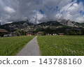 Cloud-covered rocky mountains, settlements at the foot of the mountains, and grasslands 143788160